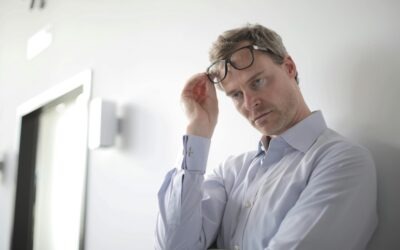 Nachdenklicher Mann lehnt an einer Wand und schiebt die Brille hoch – Vortragsbild „Innere Leere füllen“