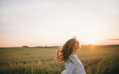 Junge Frau lacht im Abendlicht auf einem Feld – Vortragsbild „Warum dein Stress nie vergeht“