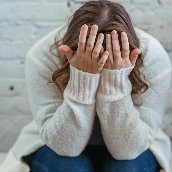 Frau hält Hände vor den Kopf als Ausdruck von Stress, Angst und innerer Überforderung