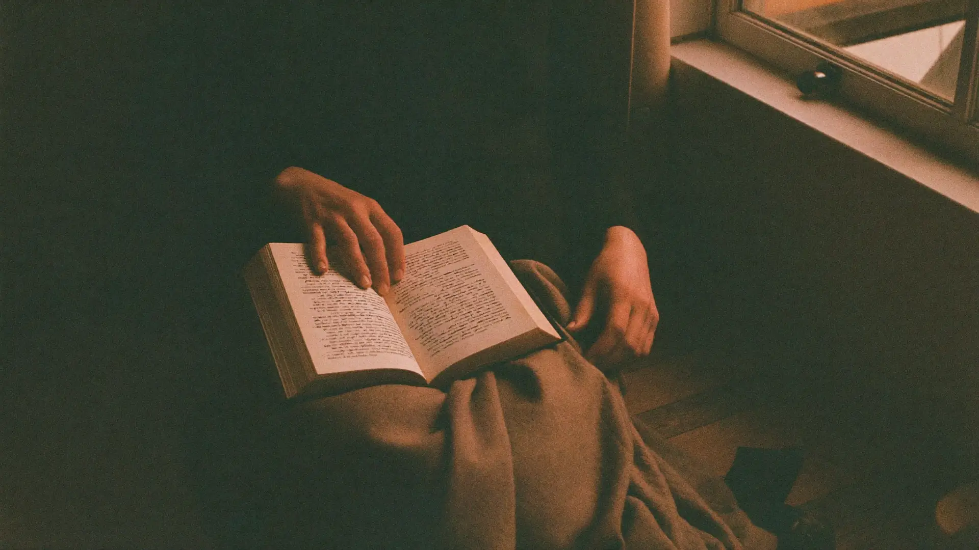 Hände halten ein aufgeschlagenes Buch auf einer Wolldecke im Morgenlicht – Mentaltraining mit geistlichen Prinzipien