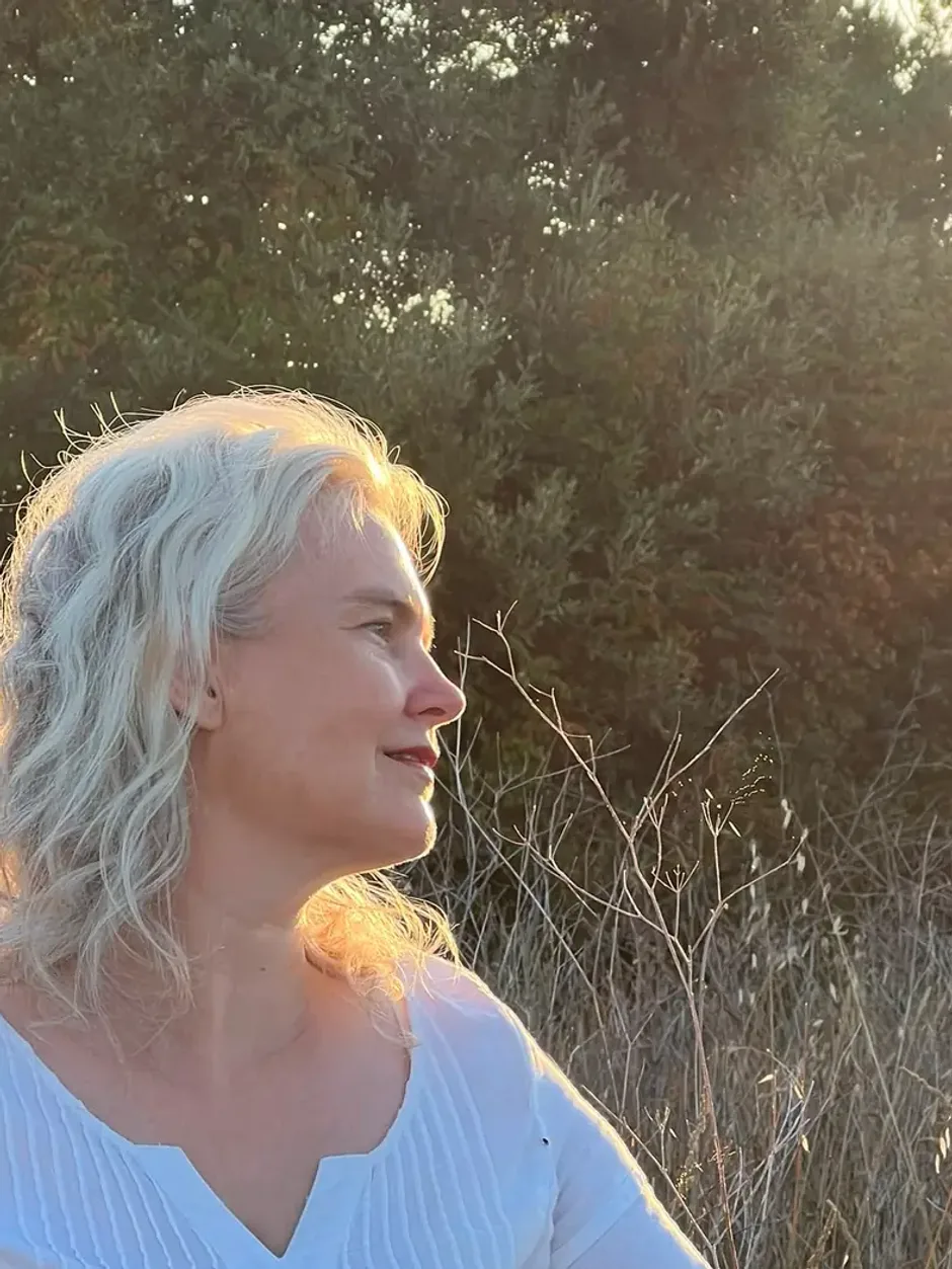 Carmen Bergmüller im Profil, Blick ins Licht, dunkle Baumreihe im Hintergrund